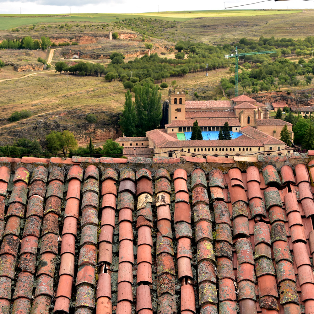 Mal aspecto de las cubiertas con cobijas en Segovia. Tejado de vivienda particular en primer plano, Monasterio de Santa María del Parral al fondo